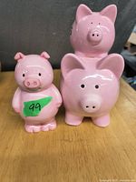 Three pink piggy banks including one small free-standing and two stacked labeled "His" and "Hers".