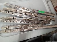 Nine metal socket storage rails placed on a flat surface showing slots for sockets and mounting holes.