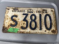 Photo showing front side of vintage 1954 Ontario license plate with rust and embossed characters.