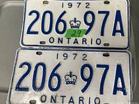 Pair of vintage 1972 Ontario metal license plates with blue embossed characters and a crown emblem, showing signs of wear and rust.