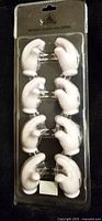 Photo of the sealed blister package containing eight Disney Mickey Mouse white plastic glove-shaped corn holders each with metal prongs.