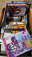 Box filled with assorted DVDs, including My Little Pony and Rise of the Guardians on top