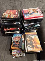 Photo showing stacks of DVDs with visible titles such as "Down with Love" and others in a pile.