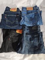 Four folded pairs of Levi's jeans and shorts in various denim colors and washes seen from back pocket side