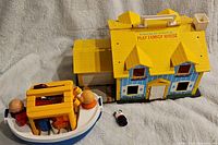 Play Family House and Play Family Boat along with small figures and accessories on a gray blanket background