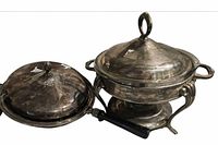 Close-up of large lidded chafing dish and medium lidded pan with black handle showing tarnish and silverplate finish