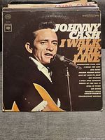 Photo of vintage Johnny Cash vinyl record album cover titled 'I Walk The Line' showing Johnny Cash holding a microphone and guitar.