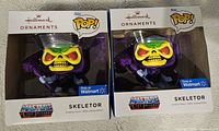 Photo showing two boxed Hallmark Ornaments featuring Funko Pop! Skeletor figures from Masters of the Universe, labeled as Walmart exclusives.