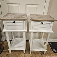 Pair of small white nightstands with distressed wood tops, front view showing drawer and lower shelf