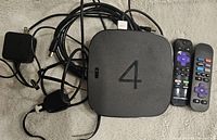 Top view of Roku 4 media streamer with '4' on top, two remotes, power adapters, and cables.