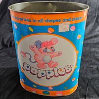 Front view of metal trash can showing central Popples character illustration and logo