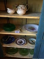 Full shelf view showing multiple ceramic, glass plates and tea set with gold accents