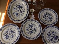Overview of 4 Blue Chatman dinner plates, 1 serving plate, Denmark egg holder, glass cream and sugar, and Ohio salt and pepper shakers on wooden table.