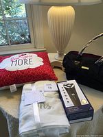 Photo showing all items including the lamp, pillow, towels, handbag, and boxed shaver on a table