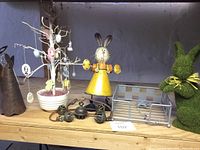 Photo of Easter tree with hanging egg ornaments, metal Easter bunny figurine, napkin holder, and green bunny figurine on shelf