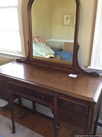 Front view of the wooden vanity table showing the table top surface, drawers, and legs. Visible wear marks and scratches on wood surface.
