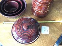 Overview shot of all items together on wooden table showing cookie jar, casserole lid, and nesting bowls.