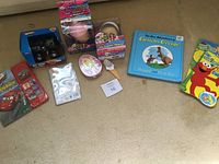 Full lot arranged on floor showing Hot Wheels cars, ice cream maker toys, books, stickers, and other small toys.