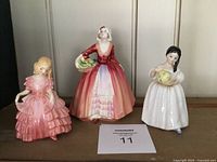 Three Royal Doulton figurines Rose, Janet, and Mandy displayed together on a shelf