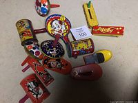 Overview photo showing assorted vintage child noise makers featuring circus and Halloween themes in colorful tin and metal construction with painted illustrations.