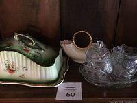Porcelain cheese dish with lid, cream vase, and glass cream and sugar set with tray on a wooden surface