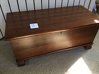 Wooden blanket chest front view showing bracket feet and keyhole on front.
