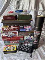 Photo of stacked boxed board games including Guess-Tures, Boogie, Super Big Boggle, Risk, Uno, Kings Corner, Chess, and a magnetic chess/checkers/backgammon set in a tube.