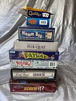 Stack of eight new/unopened board games including Quiddler, Wizard, Humm Bug, and others.