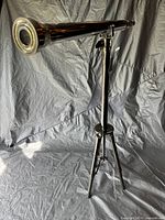 Full side view of the chrome telescope mounted on a tripod, showing the entire length and tripod legs.