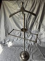 Full view of the chrome valet stand showing the wooden hanger, trouser bar, and weighted base.