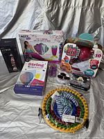 Lot of various new and unused craft kits and toys arranged on a surface, including Alex DIY fiberglass kit, Sun-Doh slime toy, Spring Arts & Crafts set, and more.