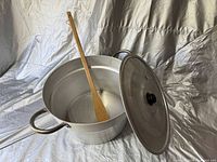 Open pot showing inside with wooden spoon resting in it, pot handles visible