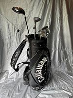 Front view of black Callaway leather Big Bertha golf bag with visible golf clubs inside, showing various club heads