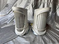 Pair of white Honeywell QuietClean compact air purifiers seen from the back and side, cords wrapped around body