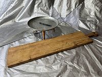 Image showing wooden charcuterie board and round metal three-legged stand on fabric background