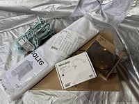 Photo of all items including packaged sofa cover, mirror box, extension cord wrapped in packaging, and lamp instructions.