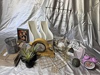 Photo of office organization and decor items displaying clocks, magazine holders, metal and ceramic decor, and small plants.