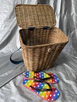 Front view showing opened wicker picnic basket and rainbow Canada Day flip-flops in front.