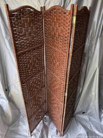 Full view of three-panel wicker room divider showing woven wicker texture, dark brown color, and hinged panel construction.