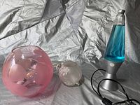 Two globe lamps and one lava lamp placed together on a surface with reflective backdrop.