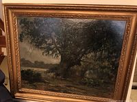 Front view of framed oil painting depicting a large oak tree by a riverbank