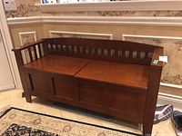 Front view of medium brown wooden bench with slatted back and paneled front.