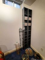 Two tall wood CD holders with dark finish, partially filled with CDs, accompanied by two metal CD holders, one large and one small, all placed in a corner of a room.