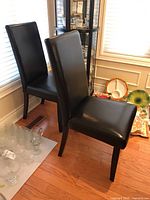 Two chairs front side view next to window and glass cabinet