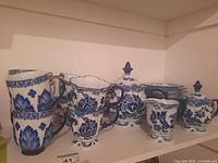 Shelf display of the full Bombay China tea set including mugs, teapot, creamer, sugar bowl and saucers in blue and white floral design.
