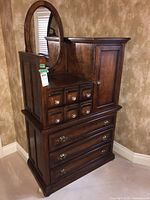 Front and side view of the dark wood dresser with oval mirror and multiple drawers.