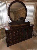Full view of wood dresser with round mirror and roll-top display section