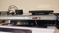LG BP540 Blu-ray player, Philips DVD642 DVD player, Asus SH-S223 DVD writer stacked together with remote and power cord.