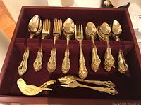 Full flatware set arranged in velvet-lined box including spoons, forks, teaspoons, salad forks, serving utensils, bird clip