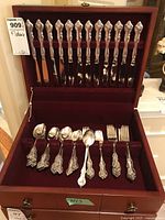 Full view of flatware set in wooden box showing knives, forks, spoons organized in velvet-lined compartments.